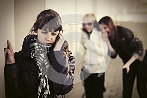 Sad teen girl calling on cell phone at the wall