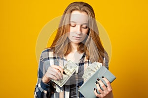 Sad teen girl with gray wallet full of money dollars