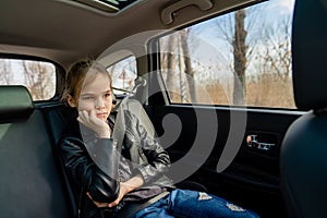 Sad teen girl in seat back of car look ahead