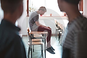 Sad boy sitting alone at school, bullying among children concept photo