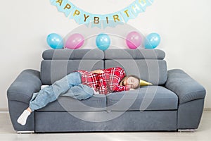A sad teenage girl are alone at home in a room decorated in honor of her birthday sleeping on the holiday, unhappy, copy space.