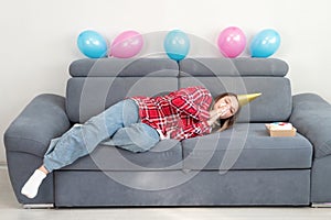 A sad teenage girl are alone at home in a room decorated in honor of her birthday sleeping on the holiday, unhappy, copy space.