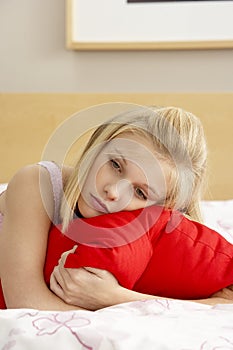 Sad Teenage Girl In Bedroom Hugging Pillow