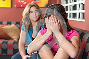 Sad teenage girl cries next to her worried mother