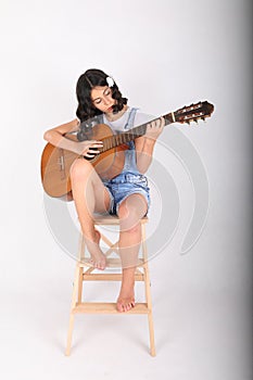 Sad teenage girl playing guitar