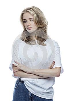 Sad teenage girl. Pretty blonde woman in a white t-shirt and jeans. Depression and negativity during puberty. Isolated on white