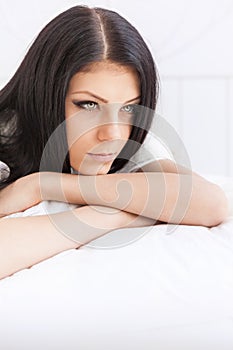 Sad teenage girl thoughtfully reflects lying on the bed photo
