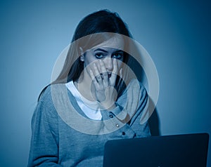 Sad teenager girl with laptop suffering bullying and harassment online. Cyberbullying concept