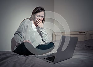 Sad teenager girl with laptop suffering bullying and harassment online. Cyberbullying concept