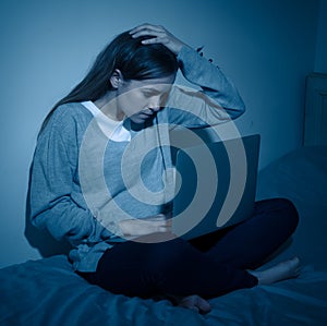 Sad teenager girl with laptop suffering bullying and harassment online. Cyberbullying concept