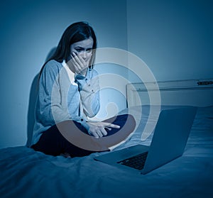 Sad teenager girl with laptop suffering bullying and harassment online. Cyberbullying concept