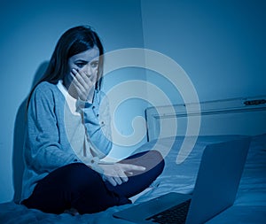 Sad teenager girl with laptop suffering bullying and harassment online. Cyberbullying concept