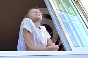 Sad teenager girl on the windowsill. Thinking cute young girl at the window. Problems baby girls