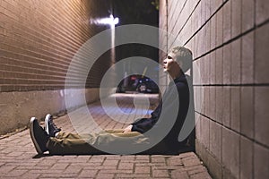 Sad teenager sitting in an alleyway.
