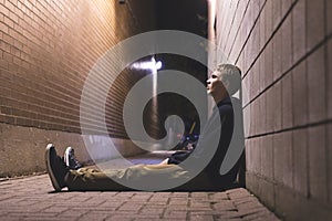 Sad teenager sitting in an alleyway.