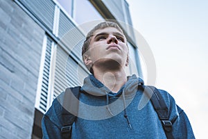 Sad teenager standing outside of a school.