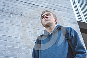 Sad teenager standing outside of a school.