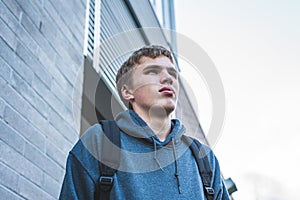 Sad teenager standing outside of a school.