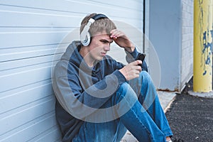 Sad teenager wearing headphones and listening to music.