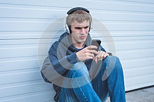 Sad teenager wearing headphones and listening to music.