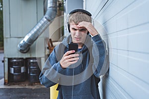 Sad teenager wearing headphones and listening to music.
