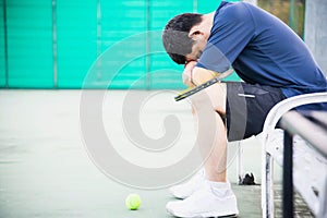 Sad tennis player sitting in the court after lose a match