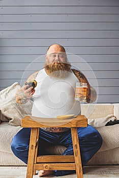 Sad thick guy eating sandwich with alcohol
