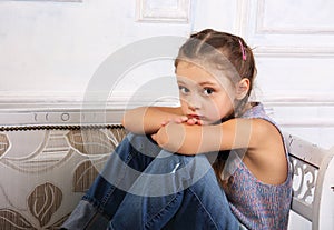 Sad thinking and dreaming kid girl sitting on the bench in blue