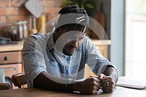 Sad thoughtful Black guy sitting at table, getting bored,