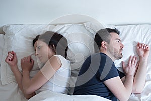 Sad and thoughtful couple after arguing lying in bed