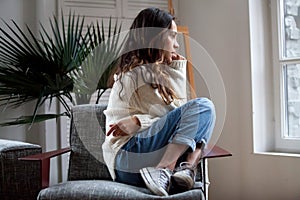Sad thoughtful girl sitting on chair feeling depressed or lonely