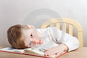 Sad tired boy in white shirt sitting at Desk