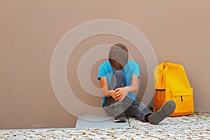 Sad, tired child sitting alone on the ground outdoors