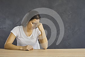 Sad tired frustrated woman sitting at table, thinking about her problems and crying