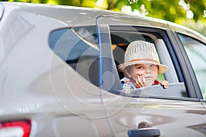 Sad tired kid boy sitting in car during traffic jam