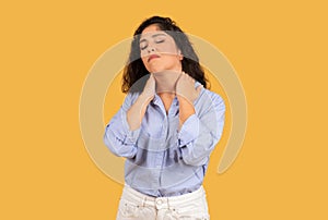 Sad tired latin young woman with long hair, massages neck with hands