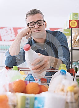 Sad man doing grocery shopping