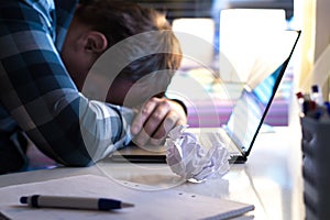 Sad and tired man in home or modern business office at night.