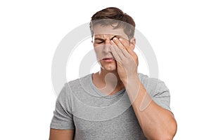 Sad tired unhappy millennial european attractive man rubs eye, suffers from pain and dryness