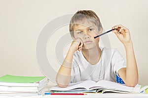 Sad tired upset child sitting at desk and doing homework at home. Education, school, learning difficulties concept