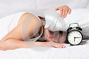 Sad tired woman waking up in the morning with alarm clock. Girl doesn` t want to wake up