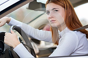 Sad tired yound woman driver sitting behind the car steering wheel in traffic jam