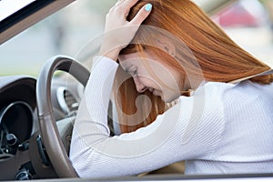 Sad tired yound woman driver sitting behind the car steering wheel in traffic jam