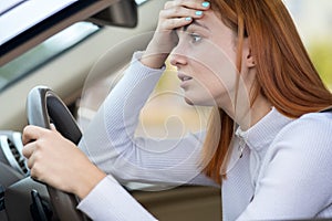 Sad tired yound woman driver sitting behind the car steering wheel in traffic jam