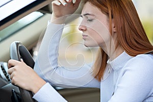 Sad tired yound woman driver sitting behind the car steering wheel in traffic jam