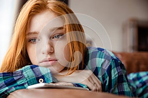 Sad tired young redhead lady thinking and listening to music