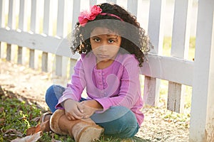 Sad toddler kid girl portrait in a park fence photo