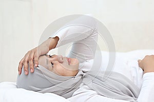 Sad unhappy Asian muslim woman lying on bed with blank stare, hard to sleep thinking of bad situation