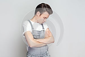 Sad unhappy brunette man standing with folded hands, frowns face upset with bad news he received.