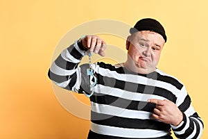 Sad unhappy fat man pointing to unlocked handcuffs hanging on his hand